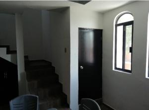 Habitación con puerta negra y escaleras con sillas en Departamento excelente zona, en Tampico