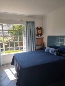 een slaapkamer met een blauw bed en een klok aan de muur bij Home away from Home in Pretoria
