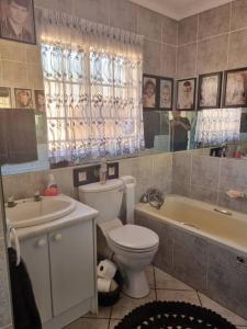 a bathroom with a toilet and a tub and a sink at Home away from Home in Pretoria
