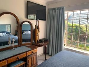 a bedroom with a dresser with a mirror and a bed at Home away from Home in Pretoria
