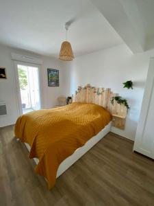 a bedroom with a large bed with a orange bedspread at Au cœur de Lacanau Océan Appartement neuf avec parking in Lacanau-Océan