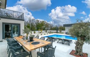d'une terrasse avec une table et des chaises en bois à côté de la piscine. dans l'établissement Nice Home In Krnica With Outdoor Swimming Pool, à Krnica