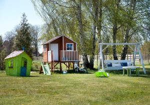 a playground with a house and a swing at Domki u Goni in Karwieńskie Błoto Pierwsze