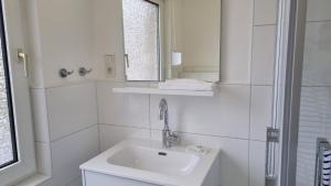 a white bathroom with a sink and a mirror at Haus Polarstern Ferienwohnung Orion in Borkum +19 photos