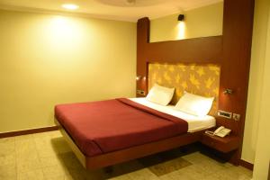 a bedroom with a bed with a red blanket at EVEREST PARK RESIDENCY in Tiruchchirāppalli
