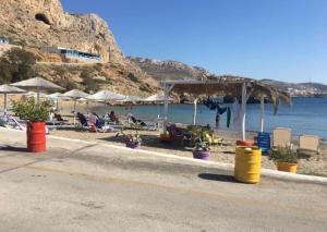 a beach with chairs and umbrellas and the water at Grannys Luxury Villas in Karpathos