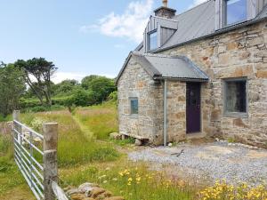 an old stone house with a fence next to it at Stone Cottage in Elgol