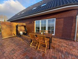 a brick patio with a wooden table and two chairs at Ferienwohnung Landblick in Steenfeld