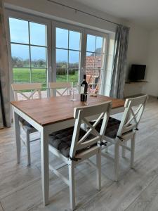a dining room table with two chairs and a bottle of wine at Ferienwohnung Landblick in Steenfeld