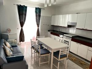 uma cozinha com uma mesa e cadeiras brancas e um sofá em La Casa di Wioletta em Barcellona Pozzo di Gotto