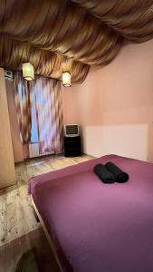 una camera con un letto viola con due cuscini neri sopra di 10/8 Kotliarska Moisha House a Lviv