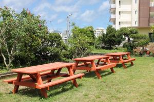 trzy stoły piknikowe siedzące w trawie w parku w obiekcie 北谷 vacation house MALAPUA w mieście Chatan