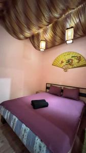 リヴィウにある10/8 Kotliarska Moisha Houseの紫色のベッド(紫色のシーツ、照明付)が備わるベッドルーム1室です。