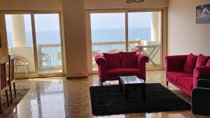 uma sala de estar com duas cadeiras vermelhas e vista para o oceano em Sea View Heart Apartment (families only) em Alexandria
