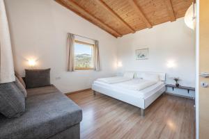 a white bedroom with a bed and a couch at Panorama Residence Schlossblick in Rodengo