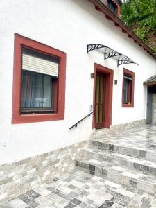 Biały dom z czerwonymi oknami i schodami w obiekcie Ferienhaus Dakaj - Einfamilienhaus w Trewirze