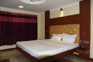 a bedroom with a large bed with red curtains at EVEREST PARK RESIDENCY in Tiruchchirāppalli