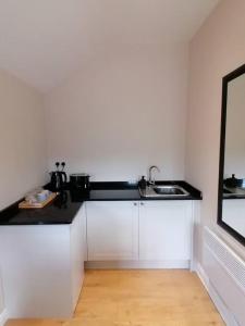 a white kitchen with a sink and a mirror at The Annexe at Entry House in Quadring