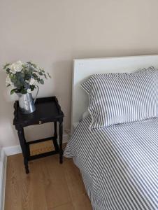a bed with a nightstand with a vase of flowers on it at The Annexe at Entry House in Quadring