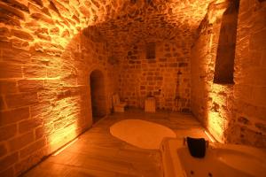 La salle de bains est pourvue d'une baignoire et de toilettes dans un mur en briques. dans l'établissement Legacy Mesopotamia Hotel, à Mardin