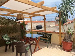 un patio con mesa y sillas bajo una pérgola en GK Apartment, en Chios