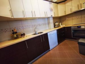 een keuken met witte kasten, een spoelbak en een vaatwasser bij Apartman Mama in Trebinje