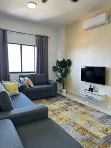 sala de estar con sofá y TV de pantalla plana en Inadh Suites @ Icon Residence With Pool, en Kuala Terengganu