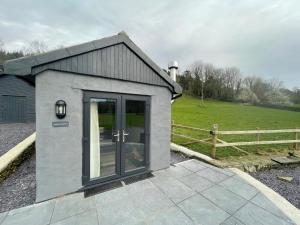 a small gray building with a door and a fence at Tyddyn Bach Bunkhouse in Betws-y-coed