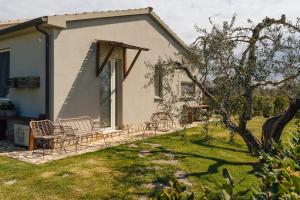 a house with a patio with chairs and a yard at Agriturismo Sweet Cottage in Marina di Grosseto