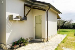a white house with a door and some plants at Agriturismo Sweet Cottage in Marina di Grosseto