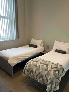 2 camas individuales en una habitación con ventana en Cosy Convenient 1 BR Flat at Central Stoke Near Hospitals and Univesities, en Stoke on Trent