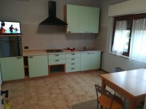 eine Küche mit weißen Schränken, einem Tisch und einem TV in der Unterkunft Affittacamere Stazione 24 in Cervignano del Friuli