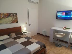 een slaapkamer met een bed, een bureau en een televisie bij Affittacamere Stazione 24 in Cervignano del Friuli