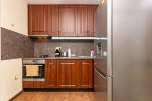 a kitchen with wooden cabinets and a stainless steel refrigerator at 2BD Penthouse: Stunning Plovdiv Views in Plovdiv
