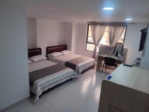 1 dormitorio con 2 camas, escritorio y TV en Hotel torre 15, en Bogotá