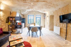 una sala de estar con mesa en un edificio de piedra en Troglo Dit Gîte 4* proche d'Amboise, en Nazelles