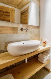 - un lavabo blanc sur un comptoir en bois dans la salle de bains dans l'établissement Chalet Le Coccole, à Sappada