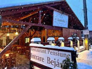 ein Restaurant im Schnee mit einem Schild davor in der Unterkunft Pensiunea Janosi - Janosi Panzio, Janosi Olga PFA in Praid