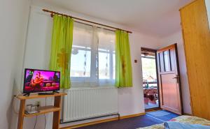 een slaapkamer met groene gordijnen, een tv en een raam bij Pensiunea Janosi - Janosi Panzio, Janosi Olga PFA in Praid