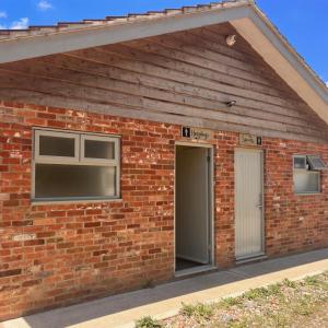 a brick building with two windows and a door at Glamping at Camp Corve in Chale