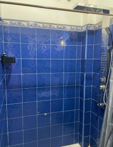 y baño con ducha de azulejos azules. en Habibi Hostel & Restaurant en Unawatuna