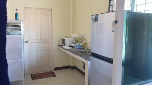 La cuisine est équipée d'un réfrigérateur blanc et d'un évier. dans l'établissement บ้านOrman, à Chumpon