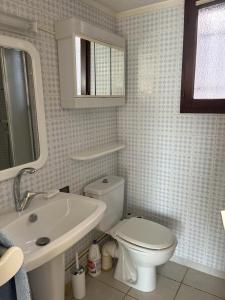 a white bathroom with a toilet and a sink at Panorama Mer in Saint Pierre La Mer