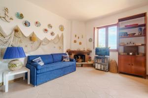 uma sala de estar com um sofá azul e uma televisão em La Pineta al Mare em Érice