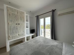 a white bedroom with a bed and a window at Naxian Touch in Agia Anna Naxos