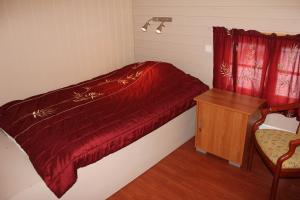 a small bedroom with a red bed and a chair at Jergul Astu in Karasjok
