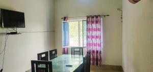 德拉敦的住宿－Gaharwar Home Stay，一间设有玻璃桌和窗户的用餐室