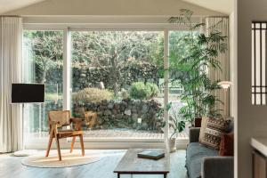 a living room with a couch and a large window at Day One Jeju Sulrem in Jeju