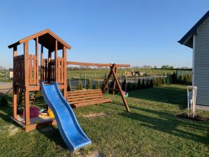 einen Spielplatz mit einer blauen Rutsche und einer Schaukel in der Unterkunft Domki u Karola in Rewal