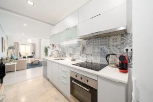 uma cozinha com armários brancos e uma sala de estar em Downtown Lux Apartment em Faro